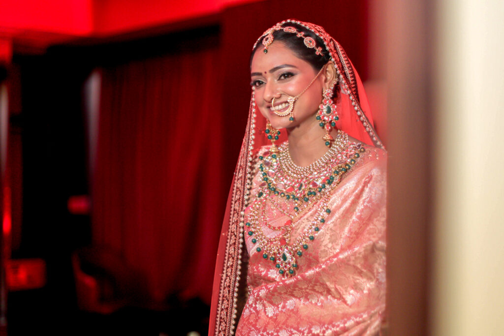 That classic bridal glow is everything! There is nothing quite like traditional silk drapery, statement jewels, and a smile that lights up the entire room. From the intricate layers of jewelry to the stunning red veil, every detail tells a timeless love story. Ready to make your wedding memories unforgettable? Let’s talk!